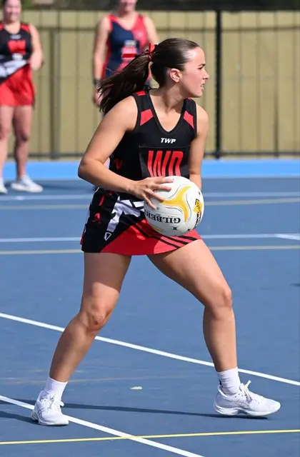 A Waaia netballer in the red and black dress with the ball