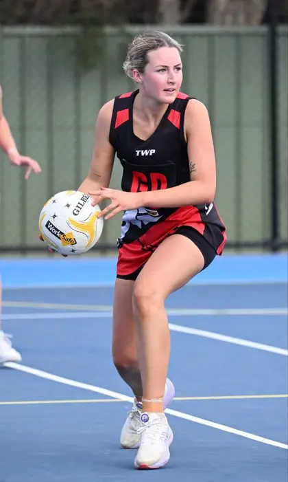 A Waaia netballer in the red and black dress with the ball