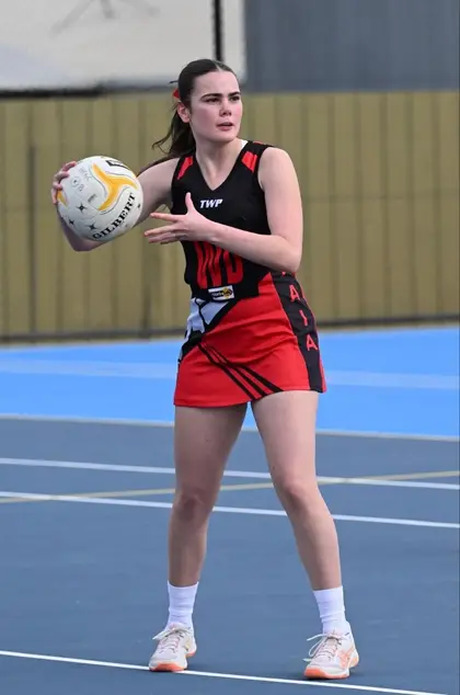 A Waaia netballer in the red and black dress with the ball