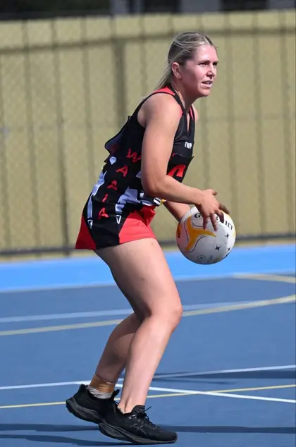 A Waaia netballer in the red and black dress with the ball